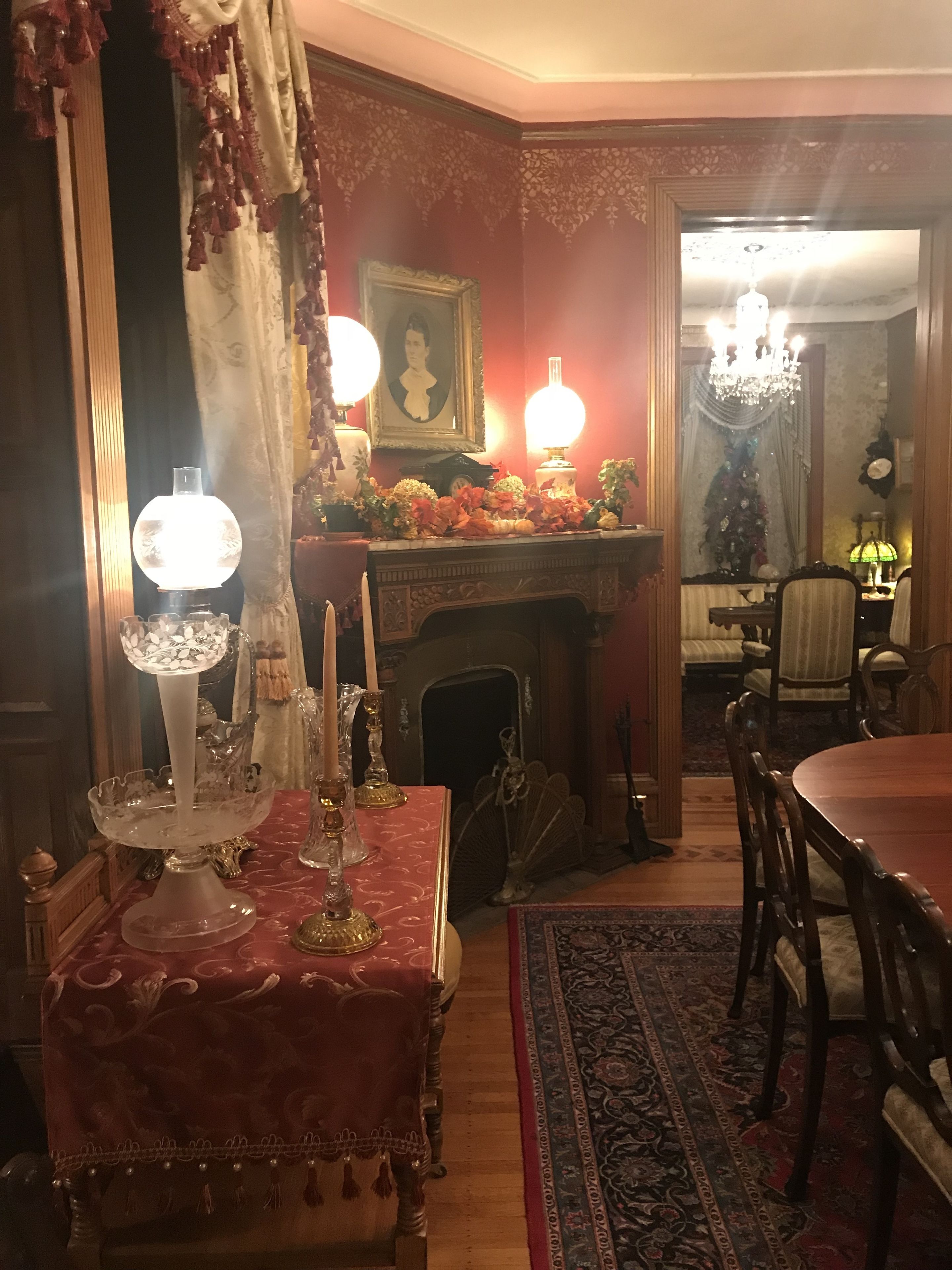 Un coin repas avec une table dressée pour deux personnes, une cheminée et un lustre.