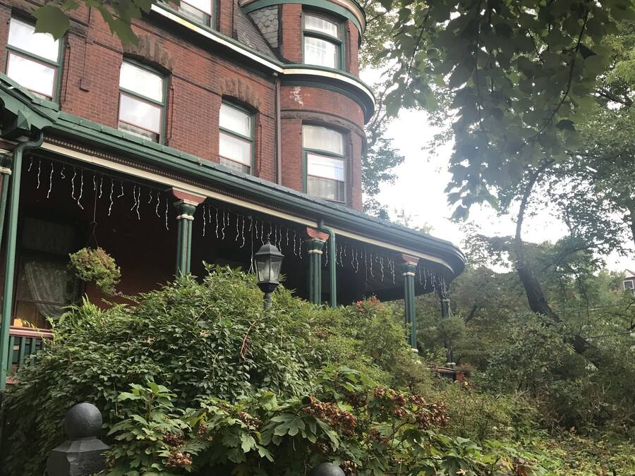 A historic building with a turret, ivy-covered walls, and a covered front porch with string lights.