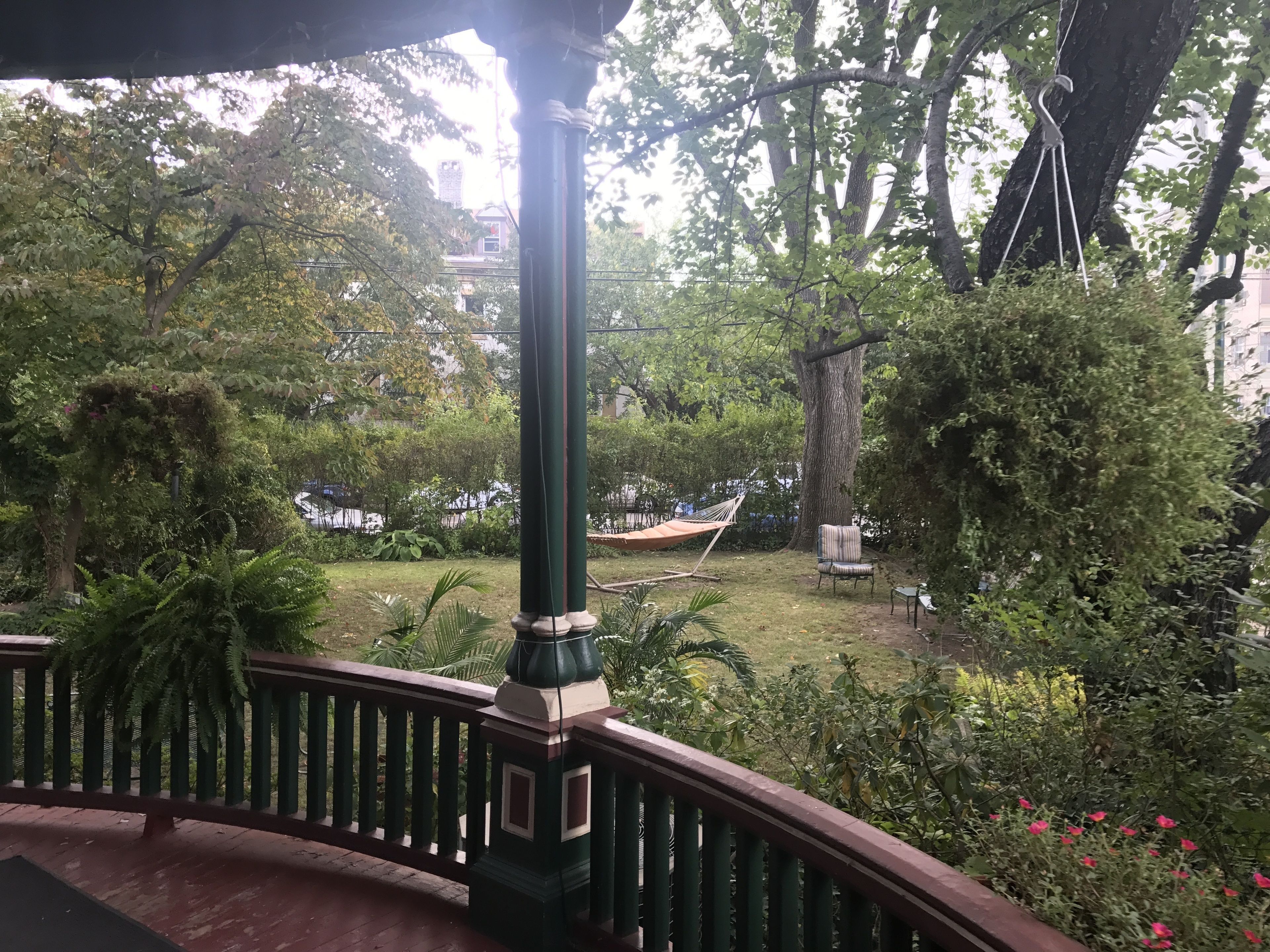 A garden area with a hammock, a chair, and a railing.