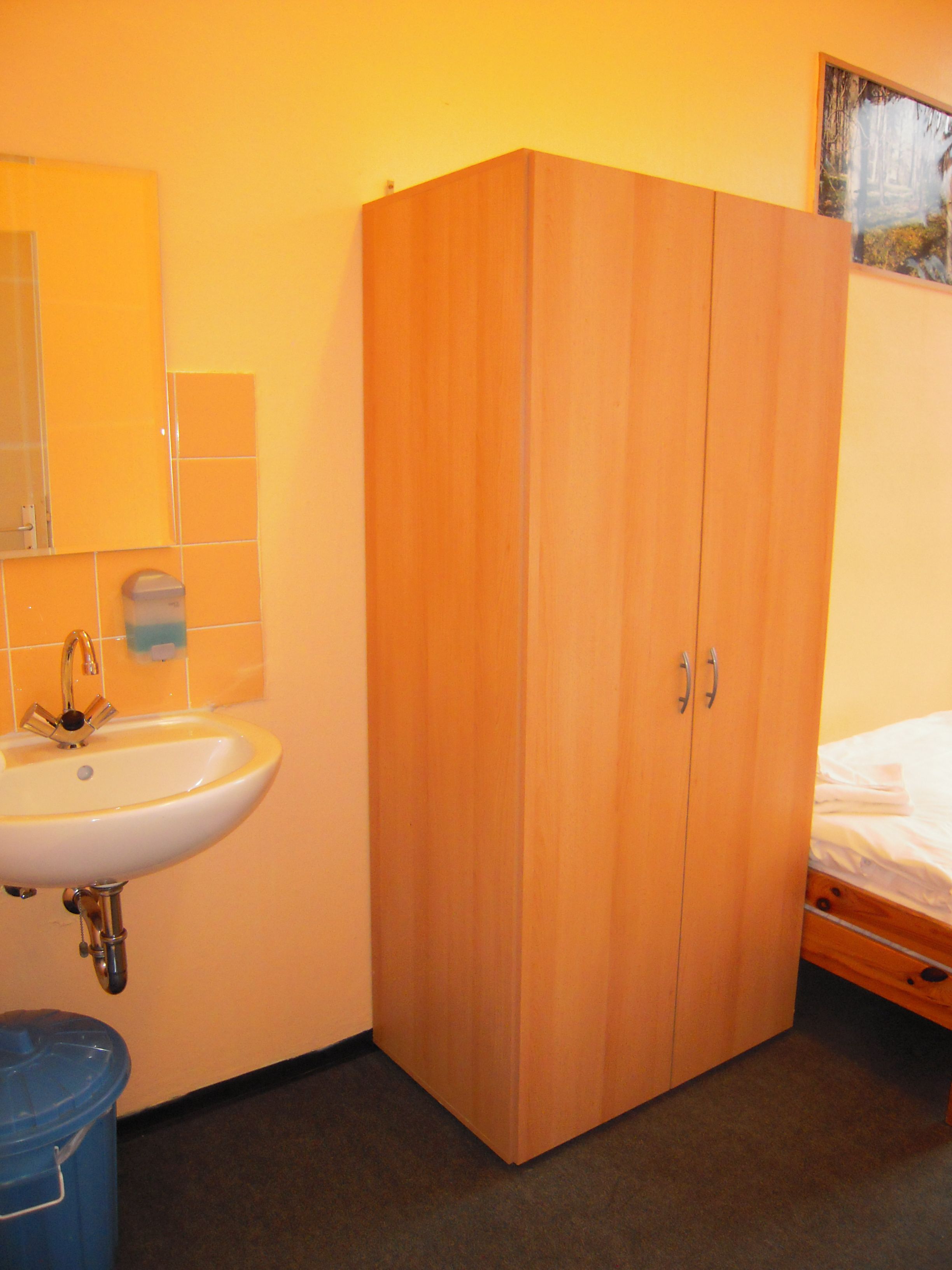 Une pièce avec une armoire en bois, un lavabo et un lit.