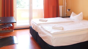 A hotel room with a bed, a desk, and a window with curtains. - HappyGoLucky Hotel & Hostel (Berlin)