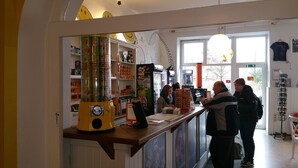 A bar area with a counter, shelves stocked with snacks, a refrigerator, and a large window. - HappyGoLucky Hotel & Hostel (Berlin)