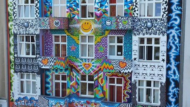 A colorful building with the sign "HappyGOLDRIGHTS" and various artistic designs. - HappyGoLucky Hotel & Hostel (Berlin)