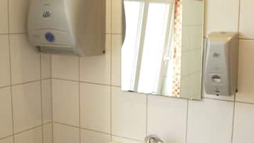 A bathroom with a white sink, a mirror, and two paper towel dispensers.