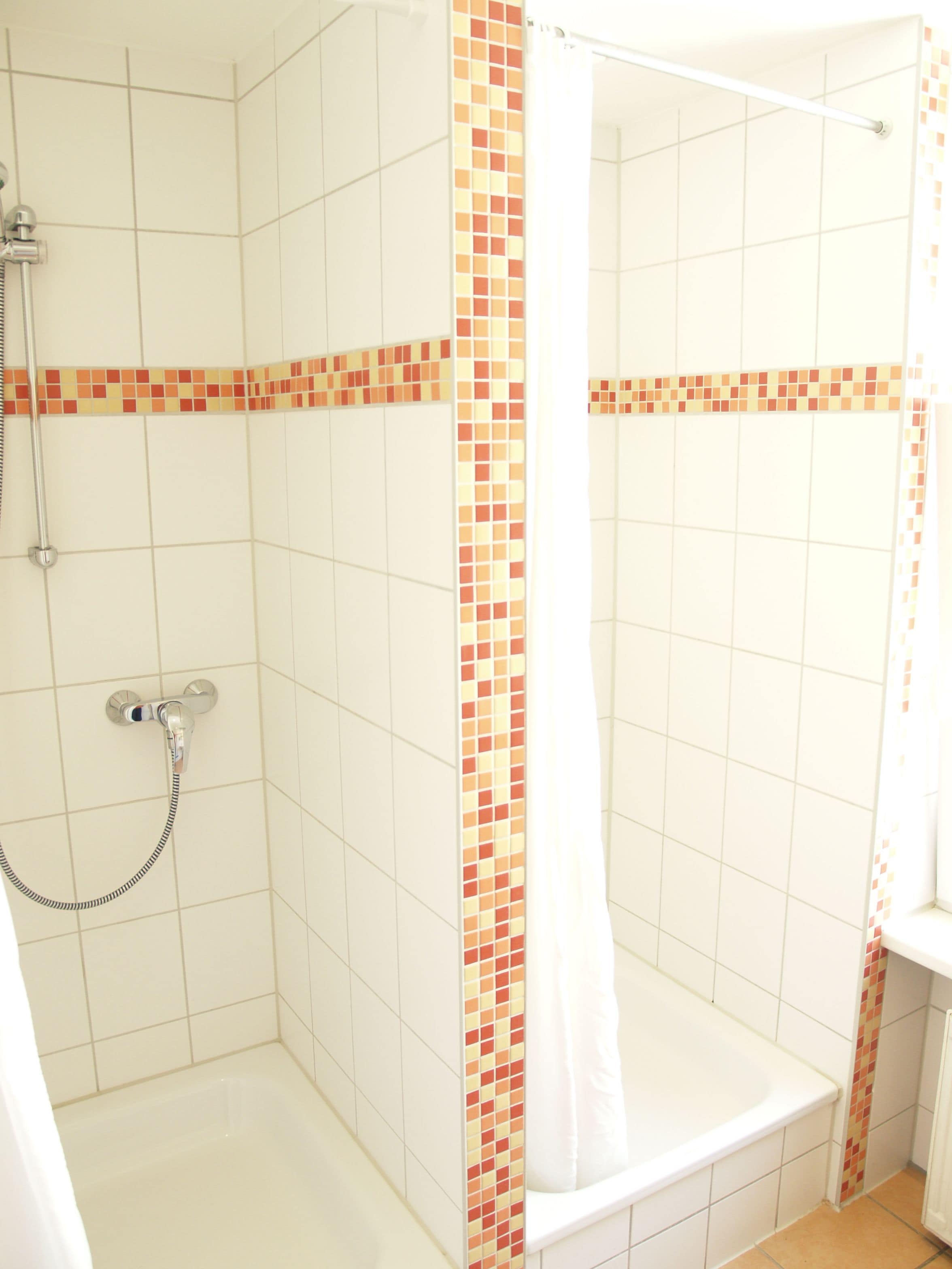 Una ducha con pared de azulejos, un cabezal de ducha y una cortina.