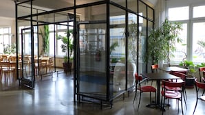 A modern interior with a glass partition, wooden furniture, and potted plants. - Hotel Transit Loft Berlin (Berlin)