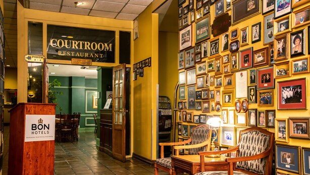 En restaurang med en skylt som visar texten ”COURTROOM RESTAURANT” och en vägg prydd med inramade fotografier.