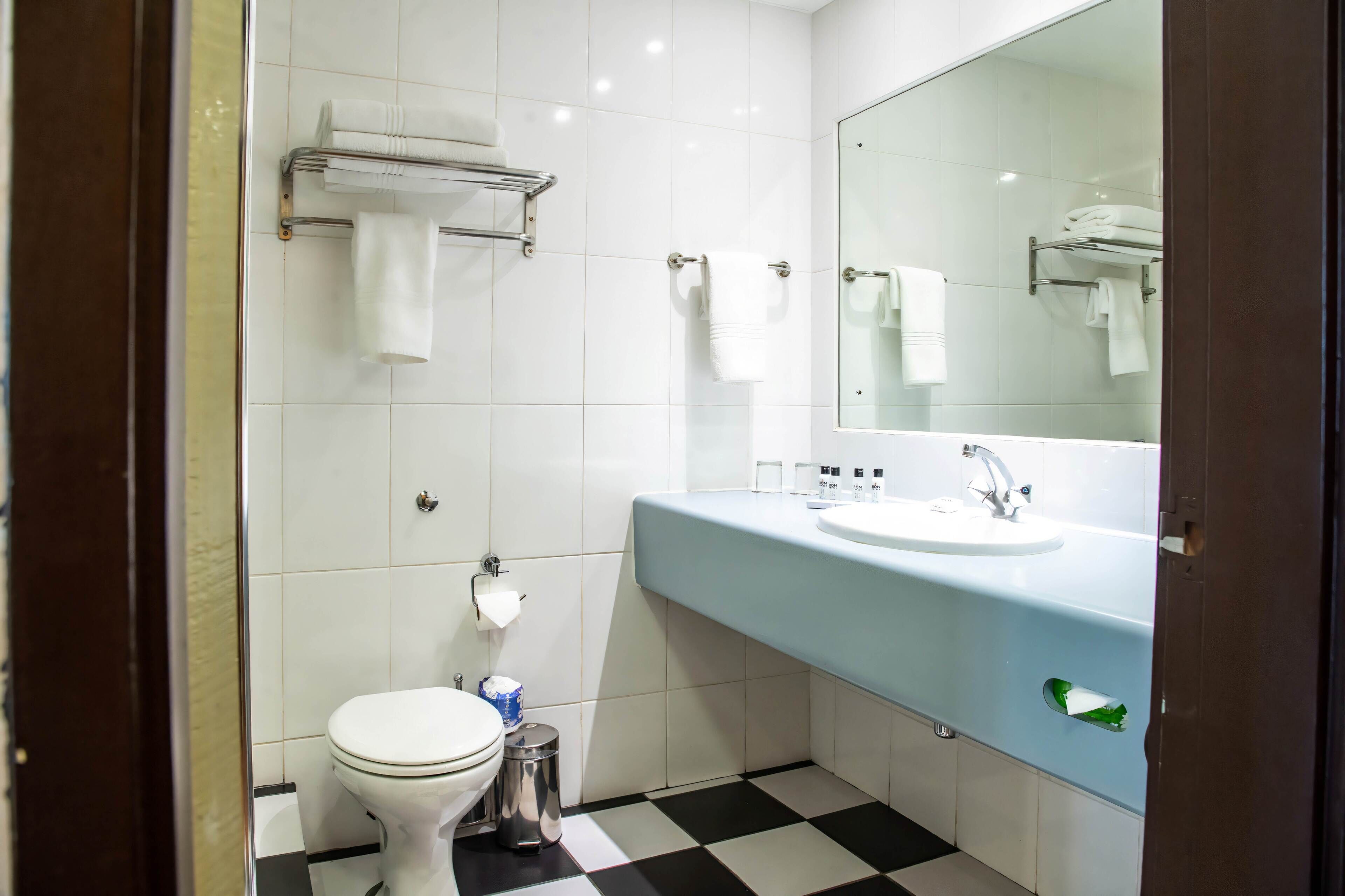 A bathroom with a toilet, sink, and towel rack.