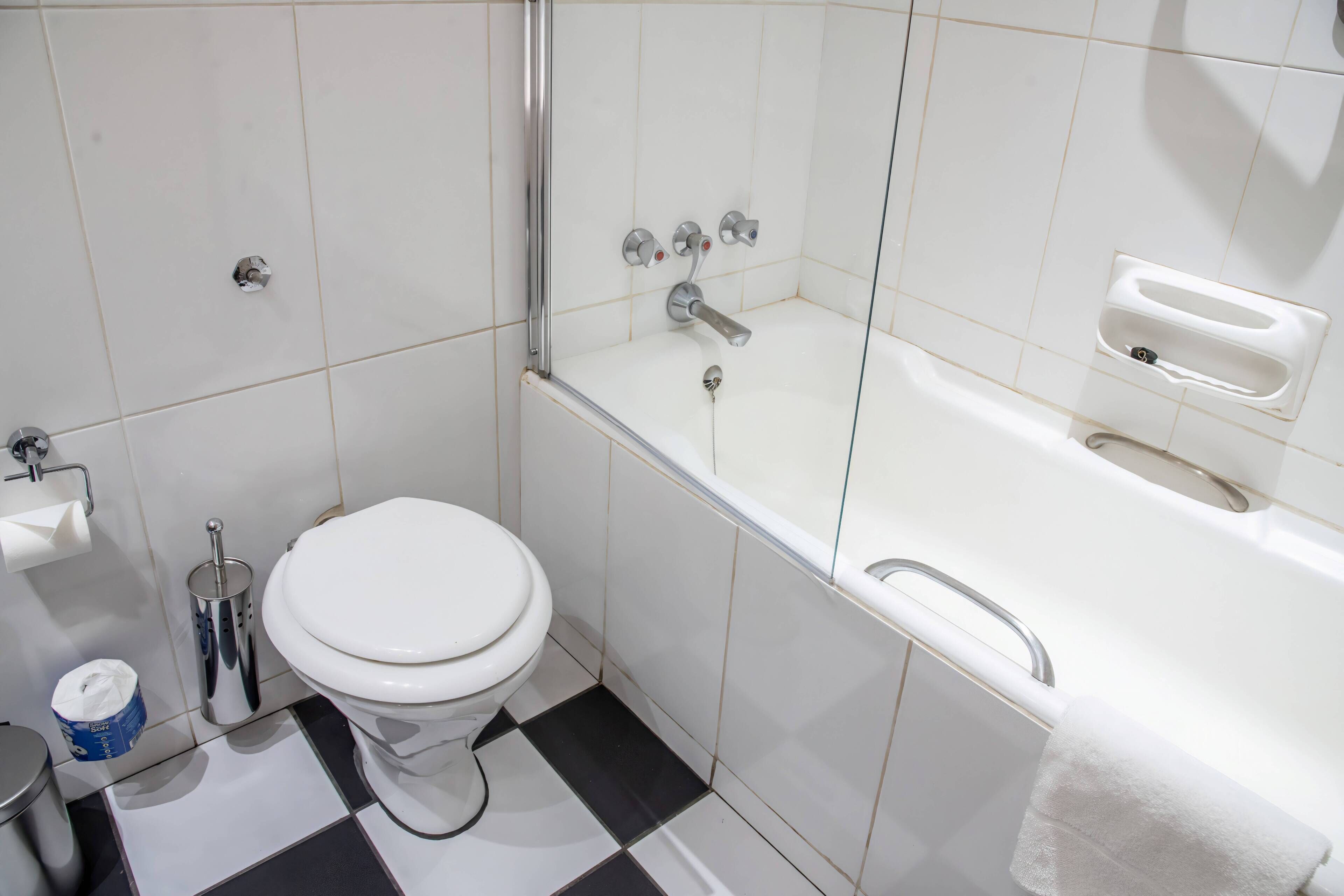 Un baño con inodoro, lavamanos, cubo de basura y bañera.