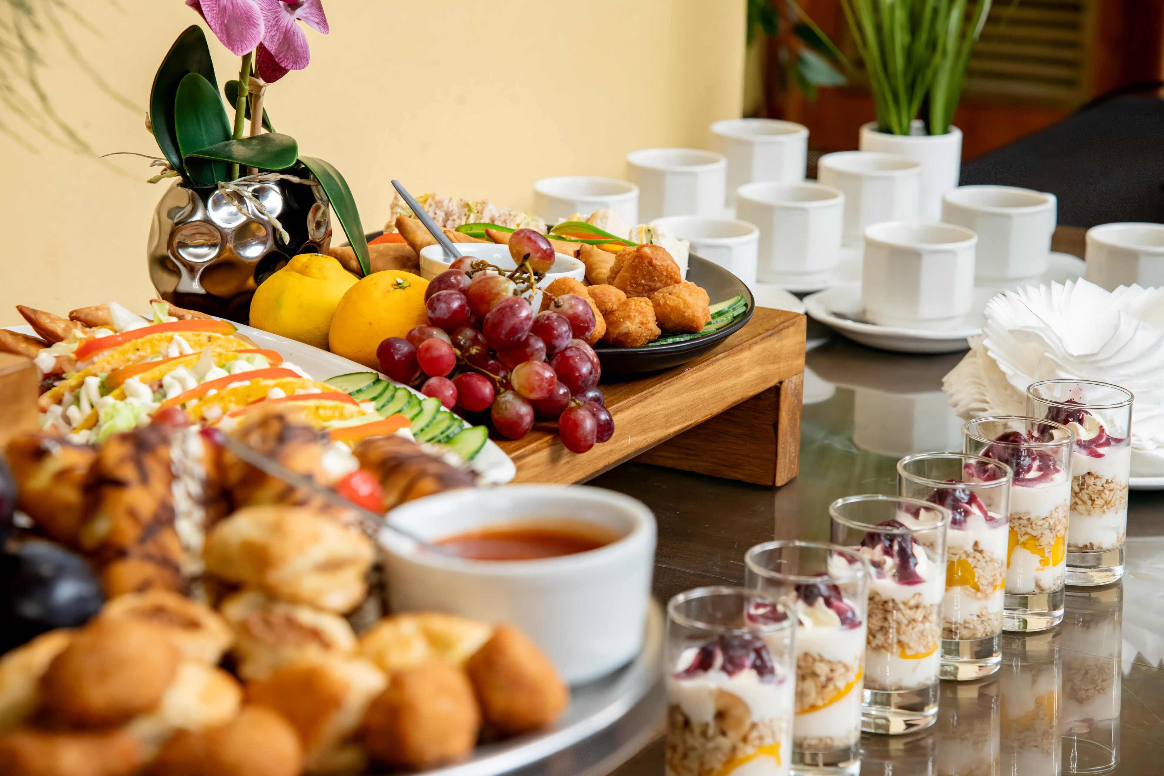 Ein Buffet mit verschiedenen Speisen, darunter Obst, Gebäck und eine Suppenschale.
