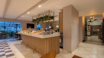 A modern hotel lobby with a central bar area, seating arrangements, and a view of the outdoors.