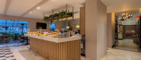 A modern hotel lobby with a central bar area, seating arrangements, and a view of the outdoors.