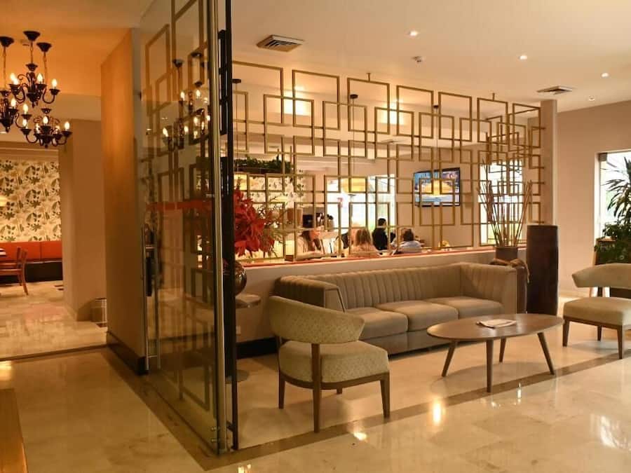Un vestíbulo con mostrador de recepción, zona de estar y un separador decorativo.