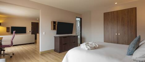 Una habitación de hotel moderna con una cama grande, un televisor de pantalla plana, un armario de madera y un escritorio con una silla.