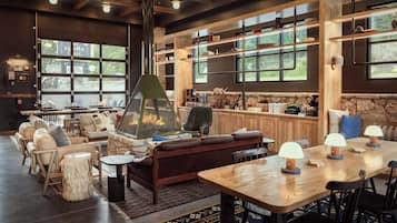 A cozy interior with a stone fireplace, wooden shelves, and a large window overlooking greenery.