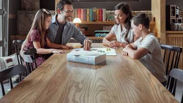 Una familia jugando a un juego de mesa en una mesa de madera, con estanterías al fondo.
