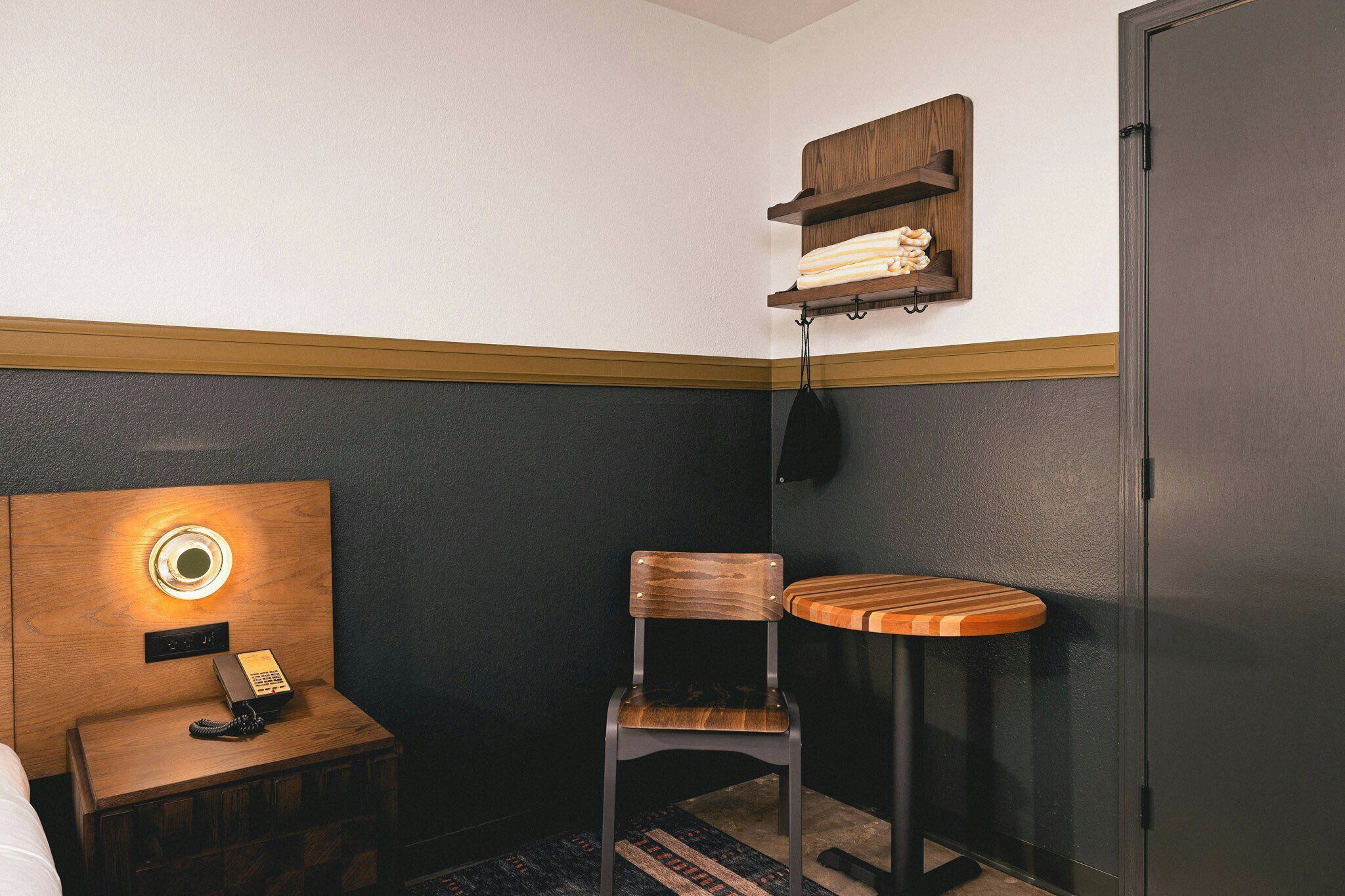 Une petite pièce, de taille modeste, comprenant une table de chevet en bois, une chaise, une petite table et une armoire.