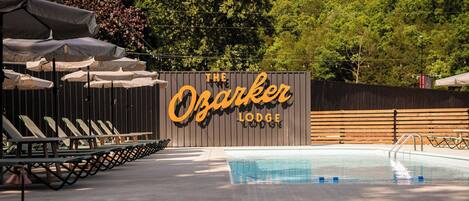 Ett poolområde med solstolar och parasoller på The Ozarker Lodge.