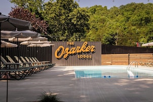 A pool area with lounge chairs and umbrellas at The Ozarker Lodge.