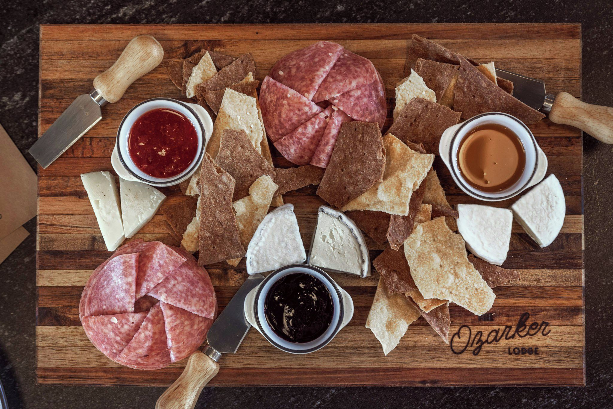 A charcuterie board with various meats, cheeses, crackers, and condiments.