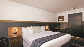 A hotel room with a bed, bedside tables, a wardrobe, and a wall-mounted shelf.