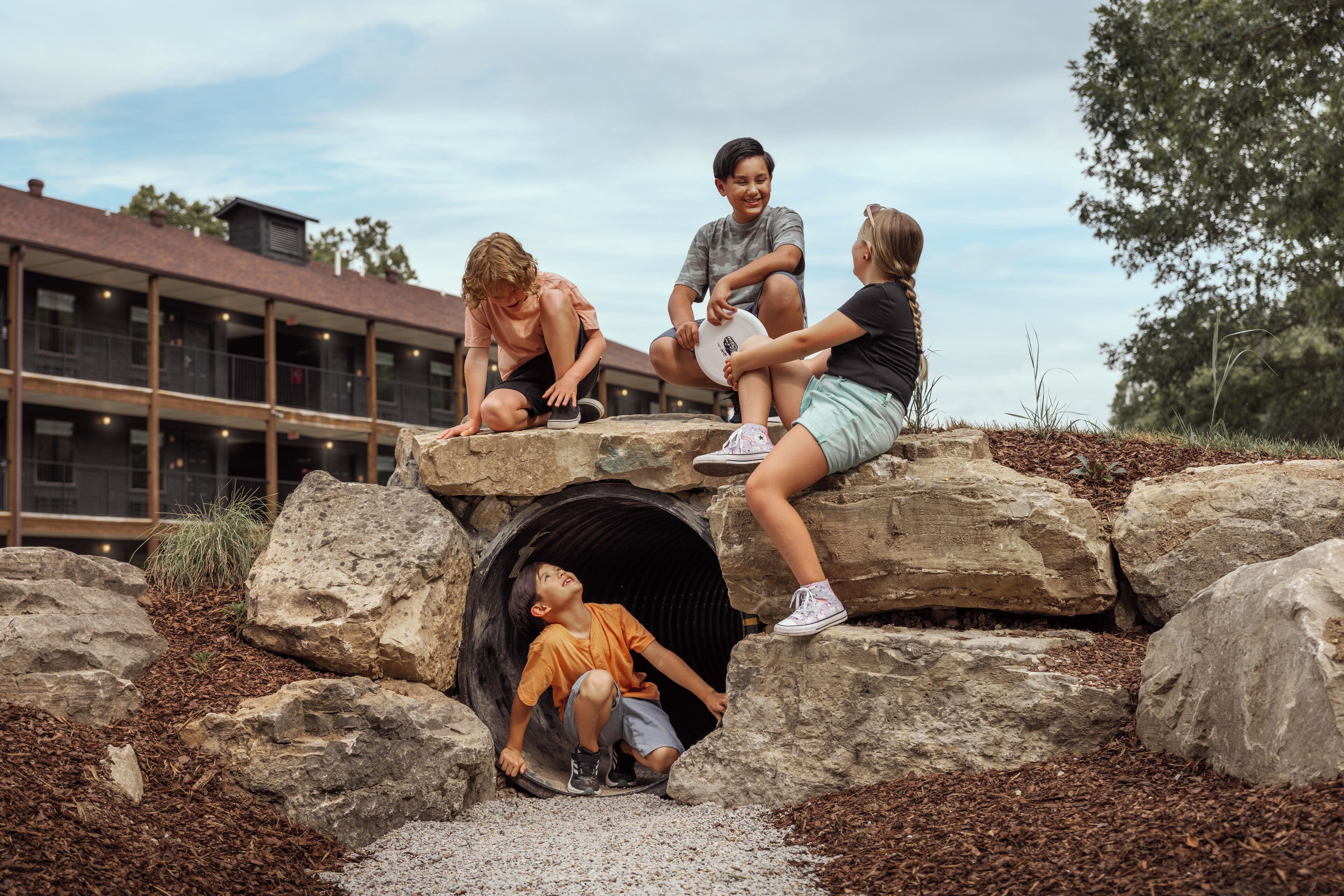 A group of people sitting on rocks with a tunnel entrance.