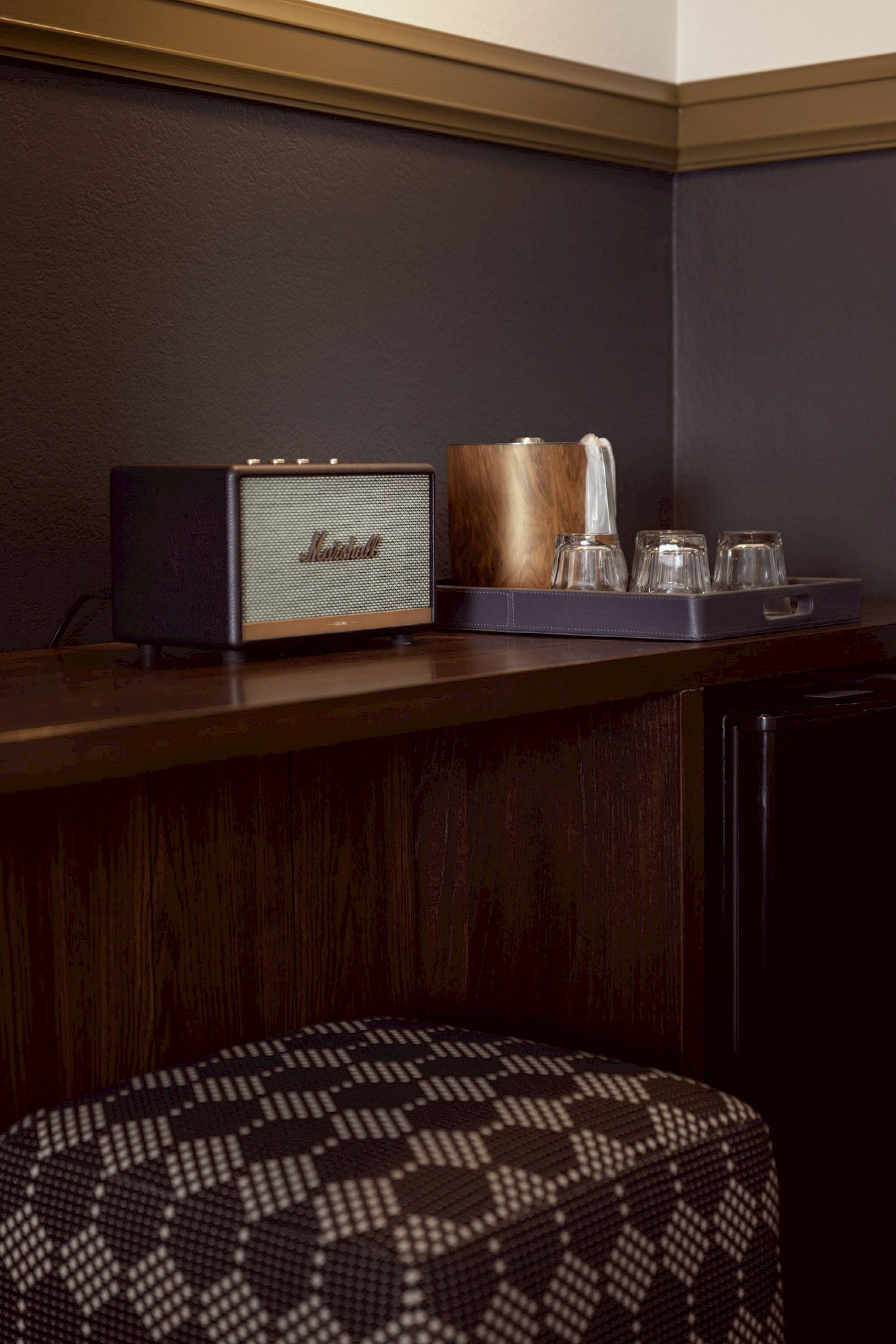 Una zona de bar con un altavoz Marshall antiguo, una barra de madera y una bandeja con vasos.
