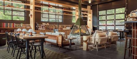 A spacious indoor area with a dining table, chairs, a sofa, and a fireplace.