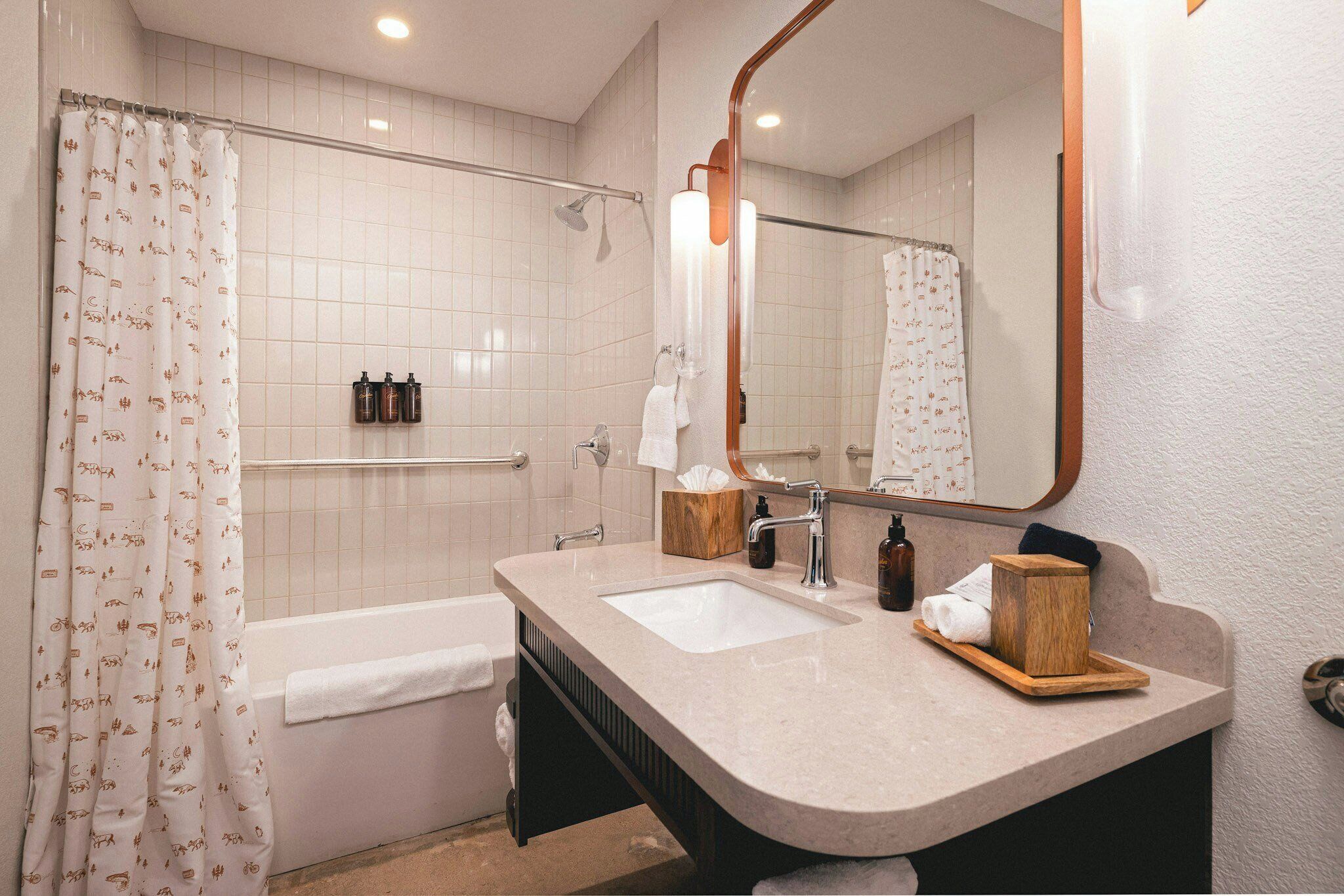Un baño con bañera, lavamanos, espejo y ducha.