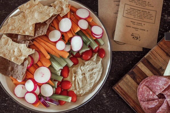 A plate with hummus, vegetables, crackers, and sliced salami. - The Ozarker Lodge (Branson)