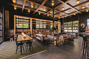 A spacious interior with a high ceiling, exposed wooden beams, a fireplace, and large windows.