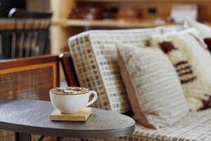 A white cup of coffee on a coaster on a round table.