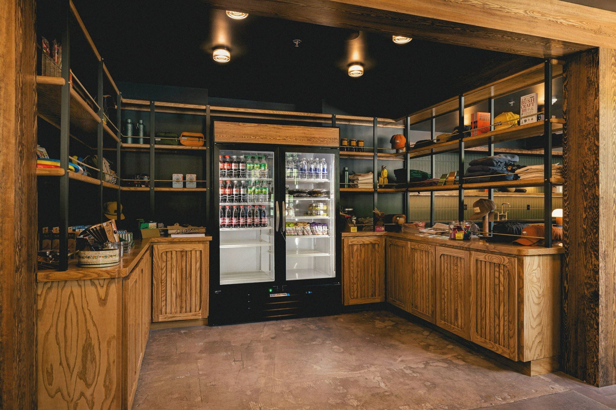 A compact kitchen with wooden cabinetry, a refrigerator, and shelves stocked with various items.