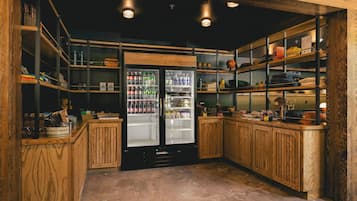 A compact kitchen with wooden cabinetry, a refrigerator, and shelves stocked with various items.