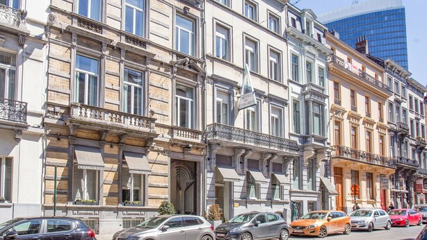A row of historic buildings with balconies, a sign for Hotel du Congres, and parked cars on the street. - Hotel Du Congres (Brussels)