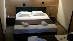 A hotel room with a large bed, two bedside tables, and a small table with towels. - Hôtel Prince De Liège (Brussels)