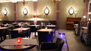 A restaurant with round tables, black chairs, and patterned upholstery. - Hôtel Prince De Liège (Brussels)
