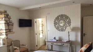 Ein Schlafzimmer mit einem Bett, einem Schminktisch, einem Sessel, einem Fernseher und einem Wanddekor.