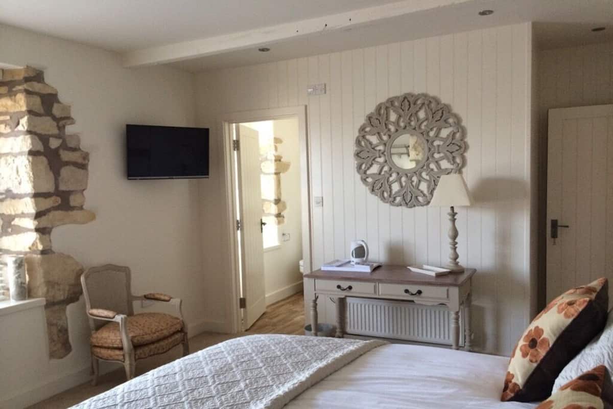 Um quarto com cama, cômoda, cadeira, televisão e um objeto decorativo na parede.