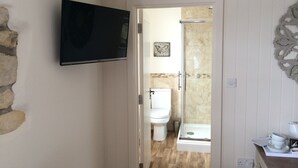 Ein Badezimmer mit Dusche, Toilette und einem Wand-Fernseher.