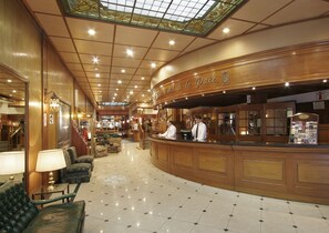 Eine Lobby mit Empfangstresen, Holzvertäfelung, einer Chandelierleuchtre und einem Fliesenboden.