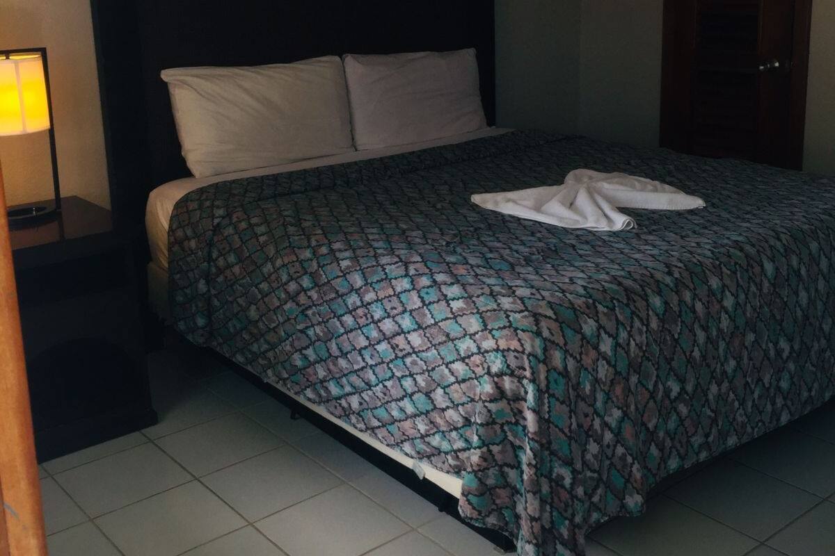 Une chambre à coucher avec un lit, une table de chevet, un ventilateur de plafond et une porte.