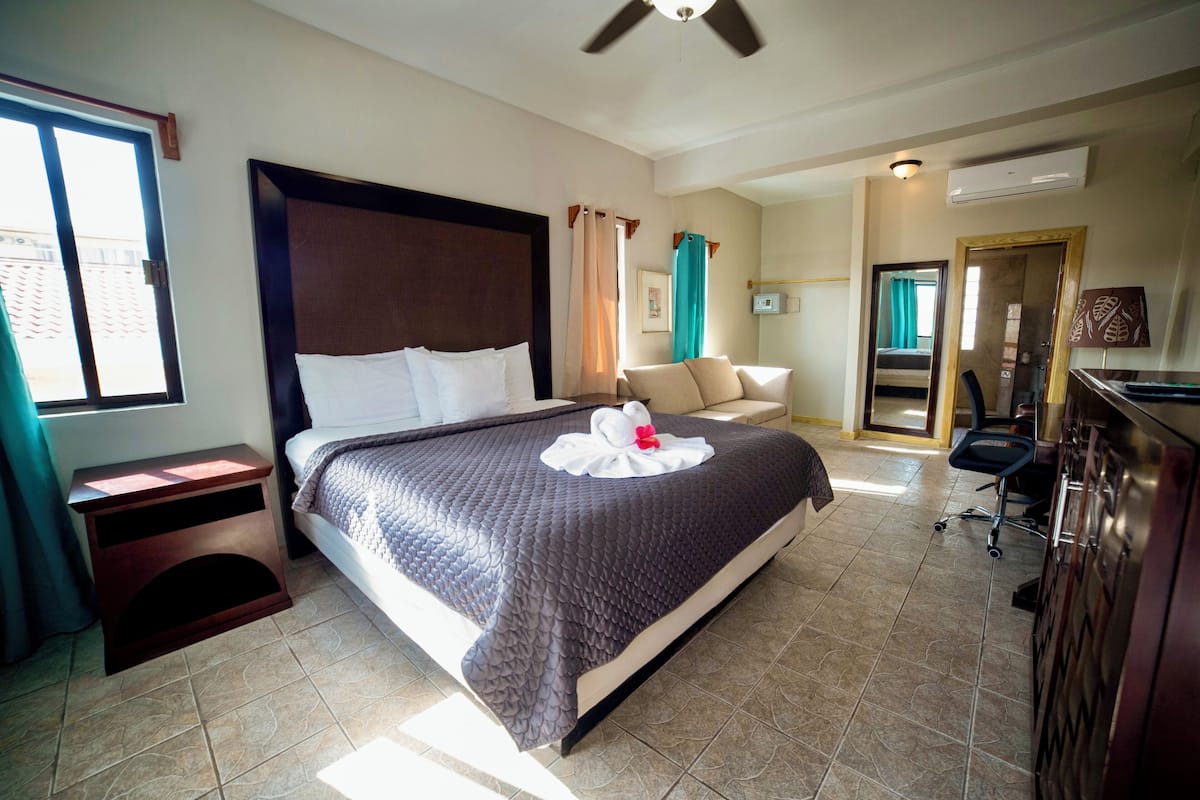 Une chambre d’hôtel avec un grand lit, un bureau, une chaise et une armoire.