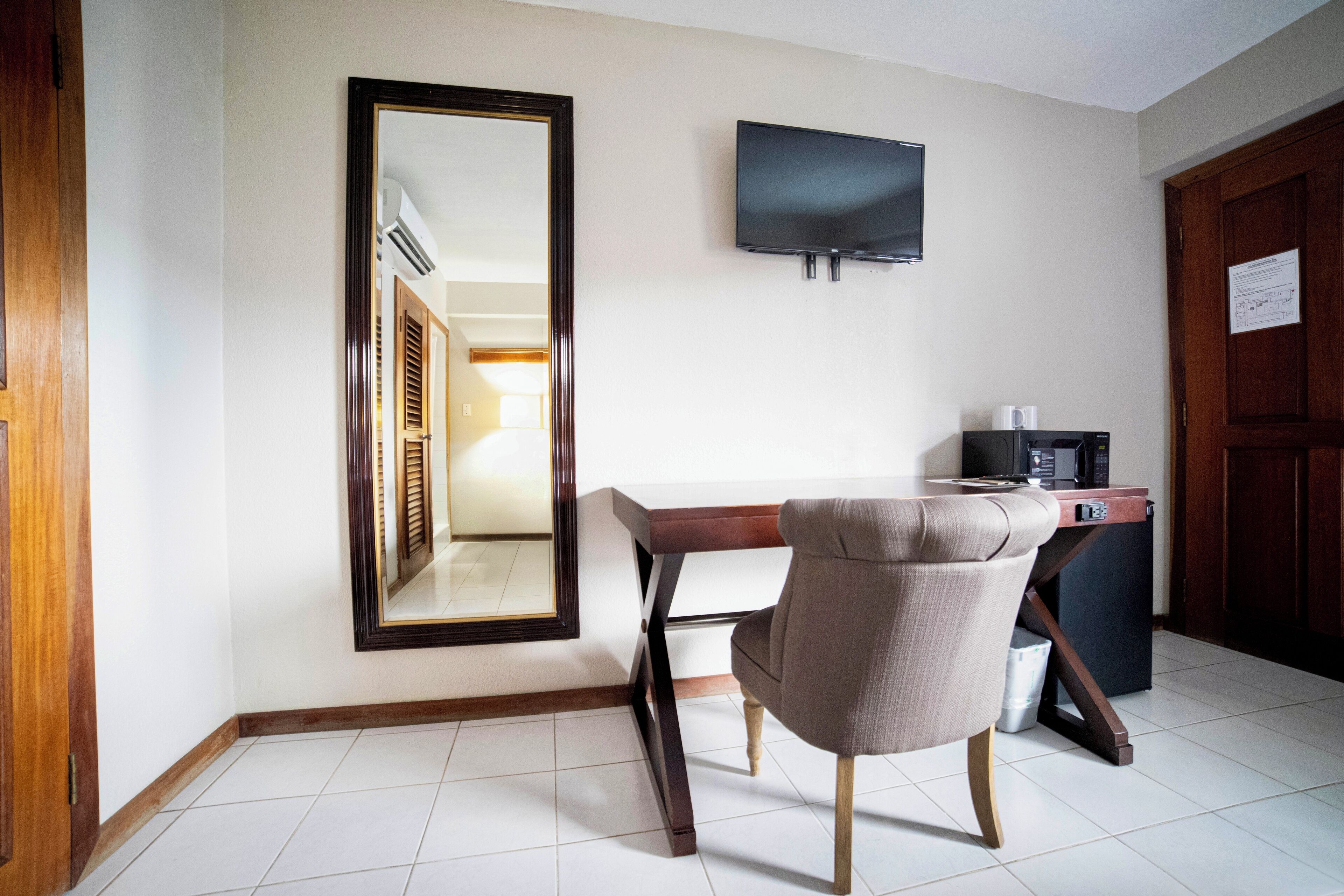 Ett hotellrum med ett skrivbord i trä, en stol, en platt-TV som är monterad på väggen och en mikrovågsugn som står på ett litet bord.