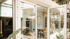 A modern building with a glass door entrance, a stone floor, and indoor plants. - Hotel Le Petit Castel (Antibes)