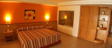 Habitación de hotel con una cama grande, dos mesitas de noche, un armario de madera y una ventana con vistas.