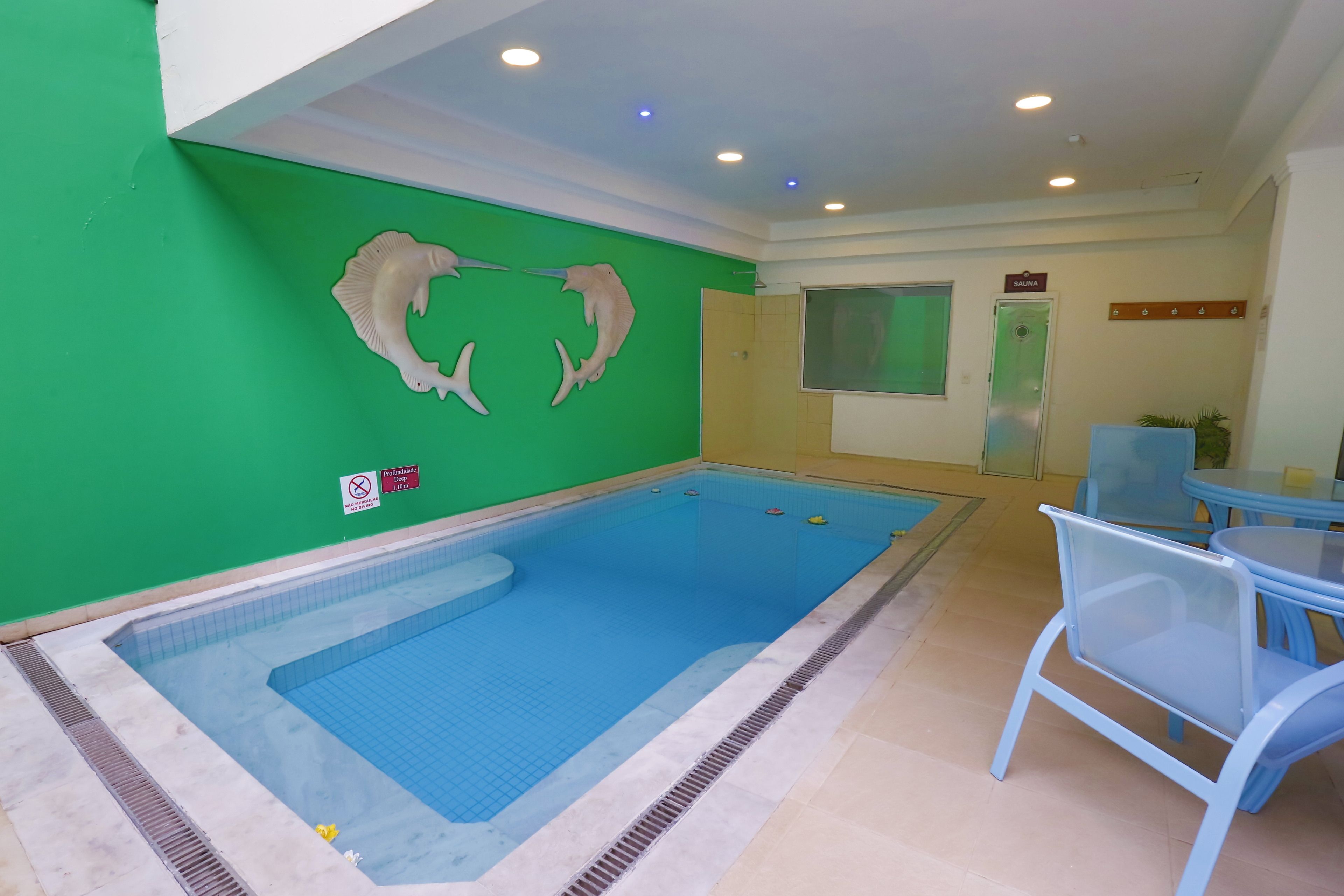 A swimming pool with a green wall and a sauna sign.