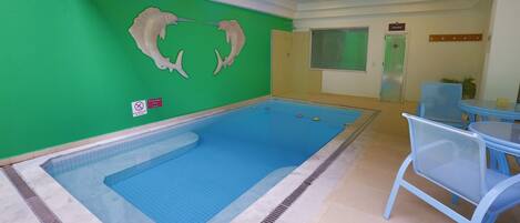 A swimming pool with a green wall and a sauna sign.