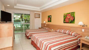 A hotel room with two beds, a TV, a phone, and a window with a view of palm trees.