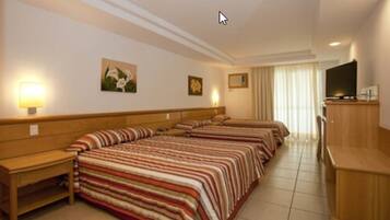 A hotel room with two beds, a TV, and a wooden desk.